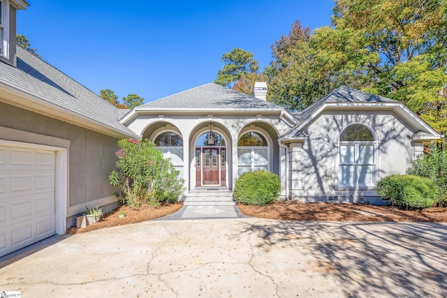 doorway to property with roof with shingles, a chimney, stucco siding, crawl space, and driveway