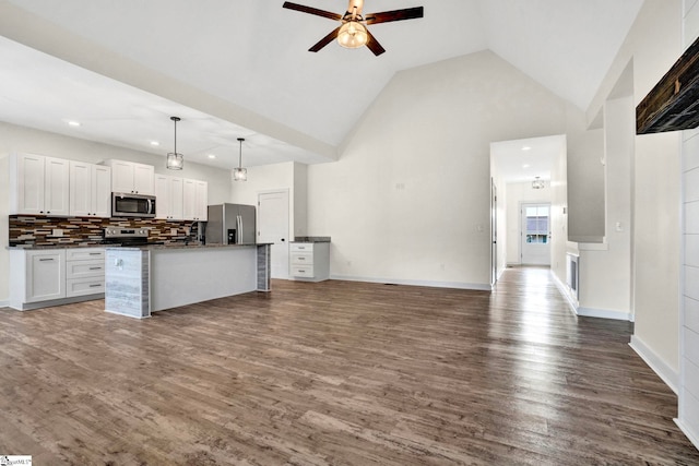 kitchen featuring a center island with sink, stainless steel appliances, decorative light fixtures, dark hardwood / wood-style flooring, and white cabinetry