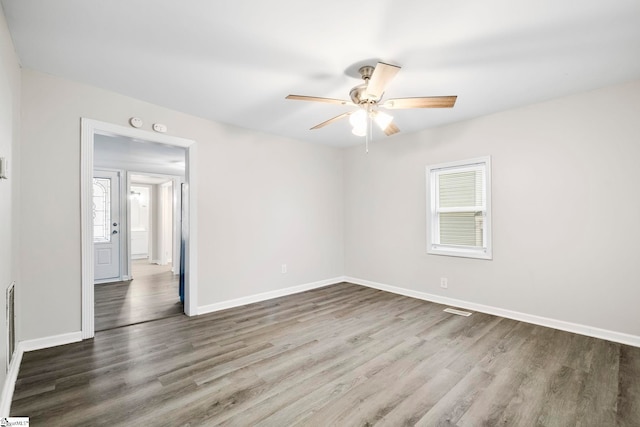 spare room featuring dark hardwood / wood-style flooring, ceiling fan, and a healthy amount of sunlight