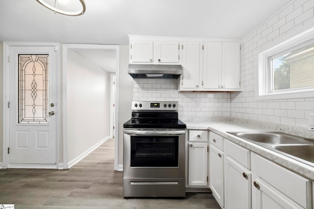 kitchen featuring white cabinetry, light wood-type flooring, sink, stainless steel electric stove, and decorative backsplash