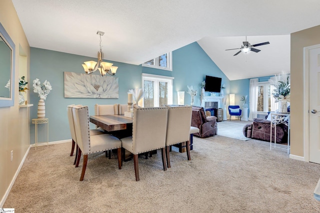 dining space featuring light carpet, vaulted ceiling, and ceiling fan with notable chandelier