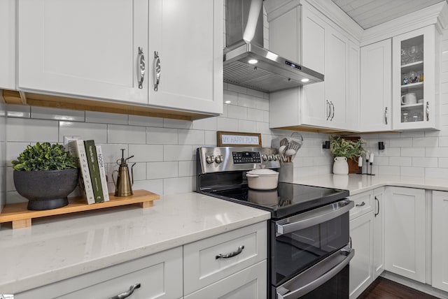 kitchen featuring extractor fan, light stone counters, double oven range, white cabinetry, and decorative backsplash