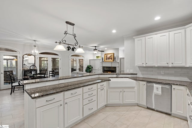 kitchen with pendant lighting, dark stone countertops, white cabinetry, a sink, and stainless steel dishwasher