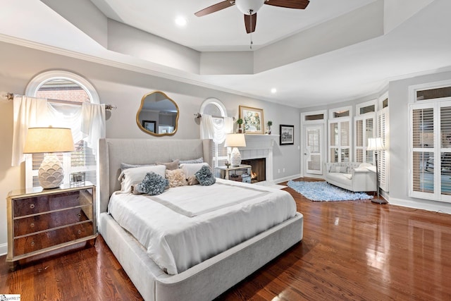 bedroom featuring dark wood-style flooring, baseboards, a fireplace with flush hearth, and recessed lighting