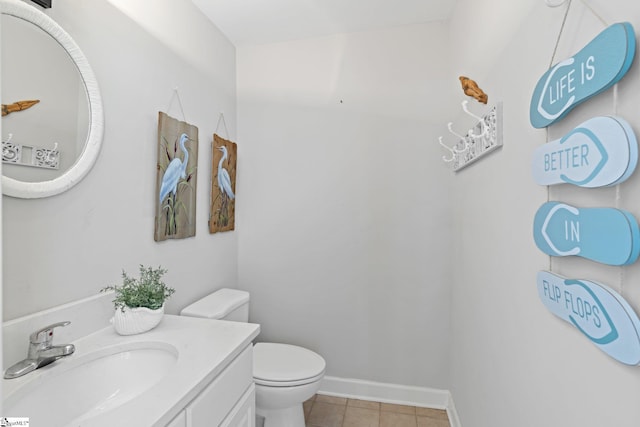 half bathroom with baseboards, toilet, tile patterned flooring, and vanity