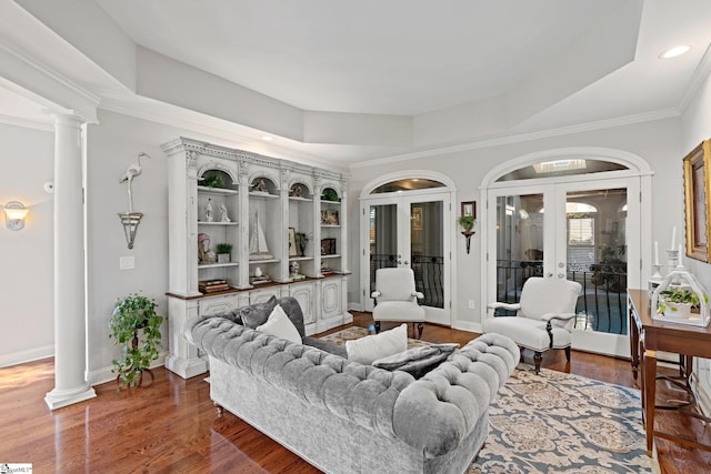 living area with a raised ceiling, dark wood-style flooring, french doors, and decorative columns