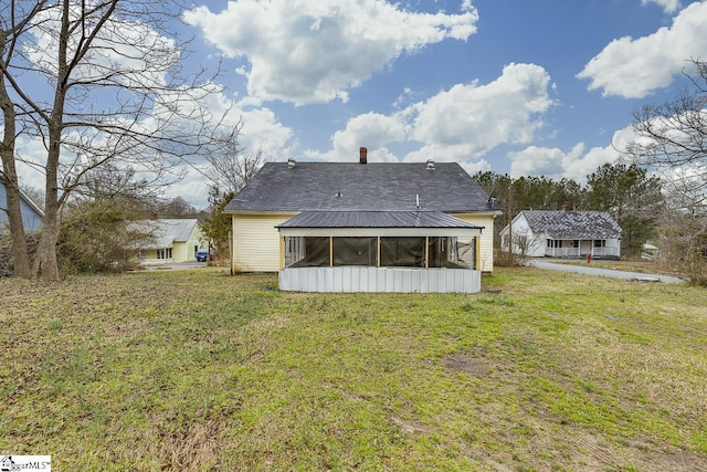 back of house with a lawn and a sunroom