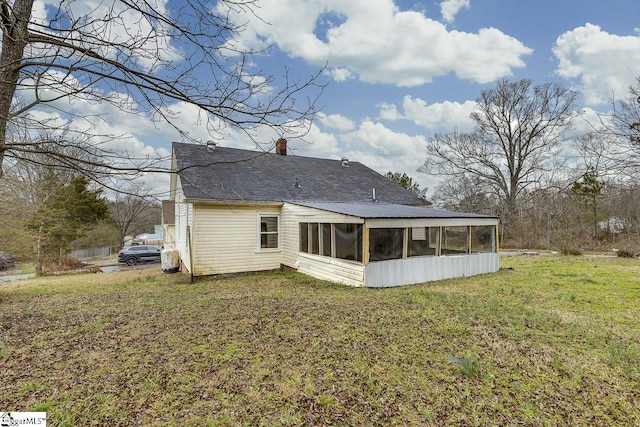 back of house with a sunroom and a lawn