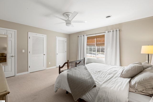 carpeted bedroom with two closets and ceiling fan