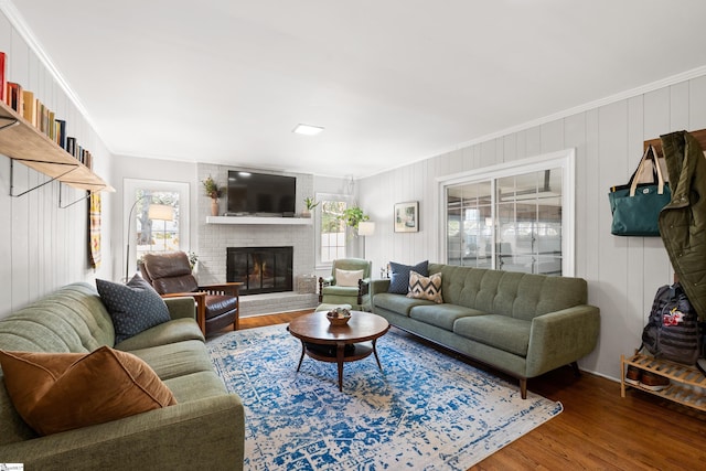 living room with ornamental molding, hardwood / wood-style flooring, and a brick fireplace