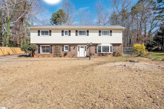 view of front of house with brick siding, a front yard, and fence