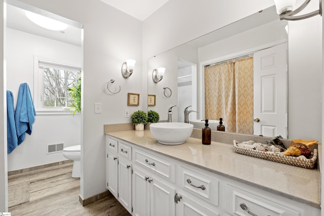 bathroom featuring toilet, hardwood / wood-style floors, and vanity