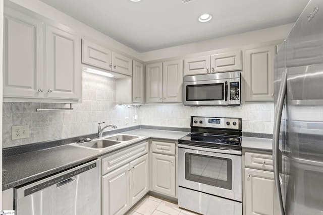 kitchen with decorative backsplash, a sink, stainless steel appliances, dark countertops, and white cabinets