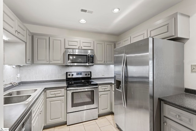 kitchen with stainless steel appliances, visible vents, dark countertops, and a sink