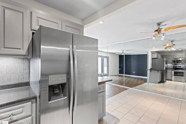 kitchen featuring dark countertops, appliances with stainless steel finishes, open floor plan, decorative backsplash, and gray cabinets