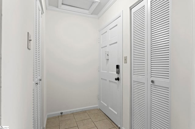 doorway to outside with baseboards, light tile patterned floors, and crown molding