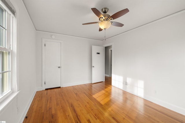 unfurnished bedroom with ornamental molding, baseboards, light wood-style floors, and a ceiling fan