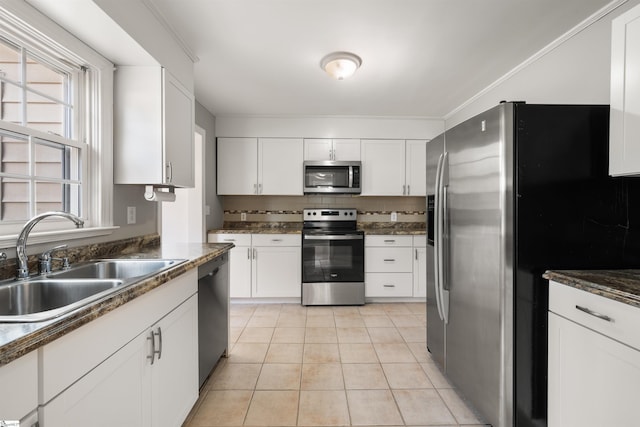 kitchen featuring decorative backsplash, a sink, appliances with stainless steel finishes, light tile patterned flooring, and white cabinets