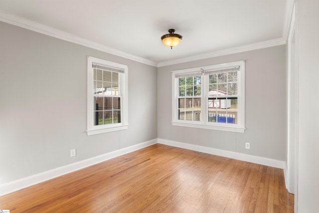 spare room featuring ornamental molding, baseboards, and wood finished floors