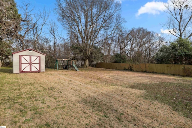 view of yard with an outbuilding, a shed, a playground, and fence