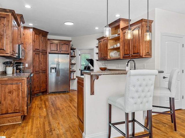 kitchen featuring open shelves, stainless steel appliances, a kitchen breakfast bar, and pendant lighting