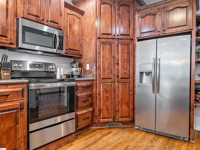 kitchen featuring light wood finished floors, visible vents, and appliances with stainless steel finishes