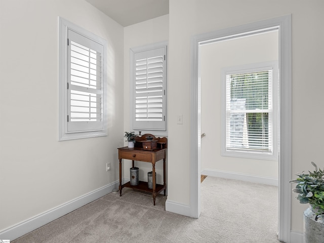 interior space with a wealth of natural light, baseboards, and light colored carpet