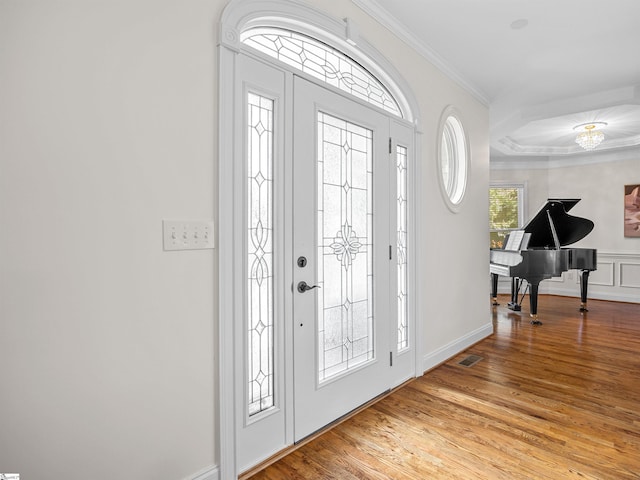 entryway with a decorative wall, light wood finished floors, crown molding, and visible vents