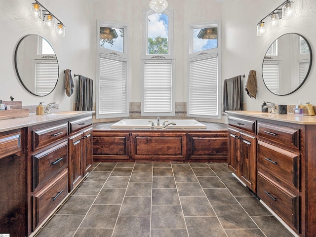 bathroom featuring two vanities, a bath, a sink, and tile patterned floors