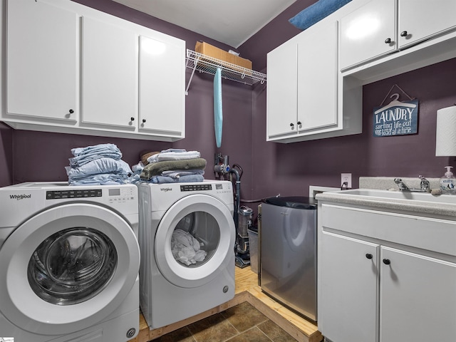 clothes washing area featuring a sink, separate washer and dryer, and cabinet space