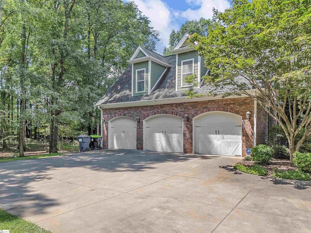 exterior space featuring brick siding, a shingled roof, an attached garage, and driveway