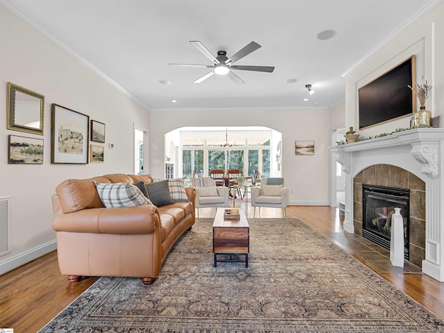 living area with baseboards, ornamental molding, visible vents, a tile fireplace, and dark wood finished floors