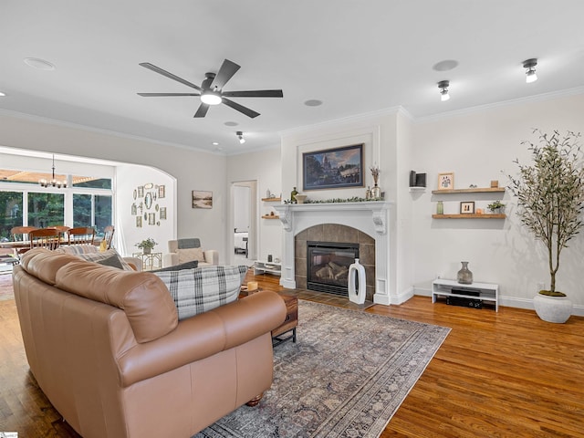 living room with ornamental molding, baseboards, a fireplace, and wood finished floors