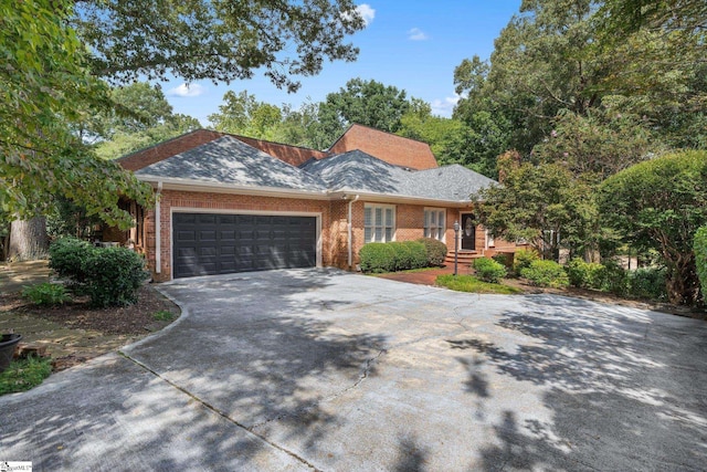 ranch-style home with brick siding, a shingled roof, an attached garage, and driveway