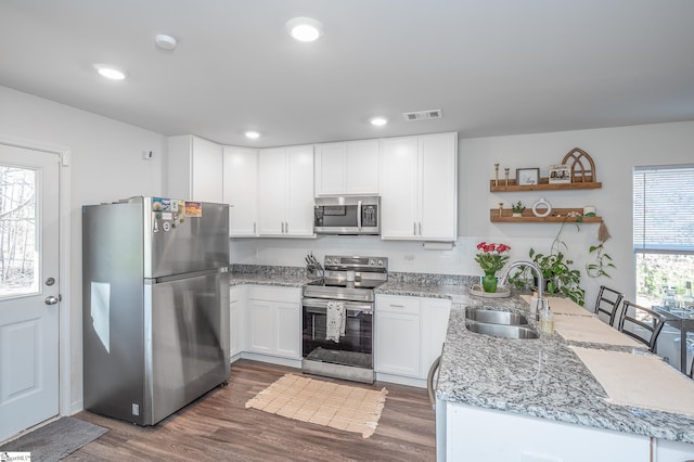 kitchen featuring a sink, visible vents, white cabinets, stainless steel appliances, and open shelves