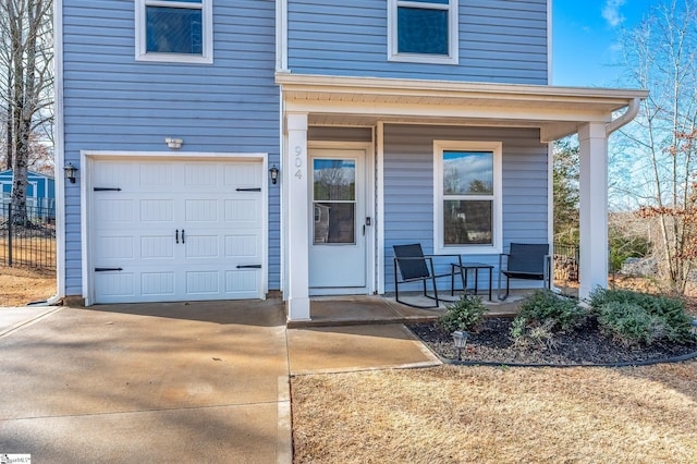 property entrance with concrete driveway, covered porch, and an attached garage