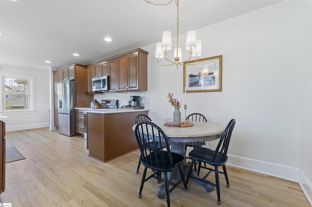 kitchen featuring decorative backsplash, light wood-style flooring, appliances with stainless steel finishes, light countertops, and pendant lighting