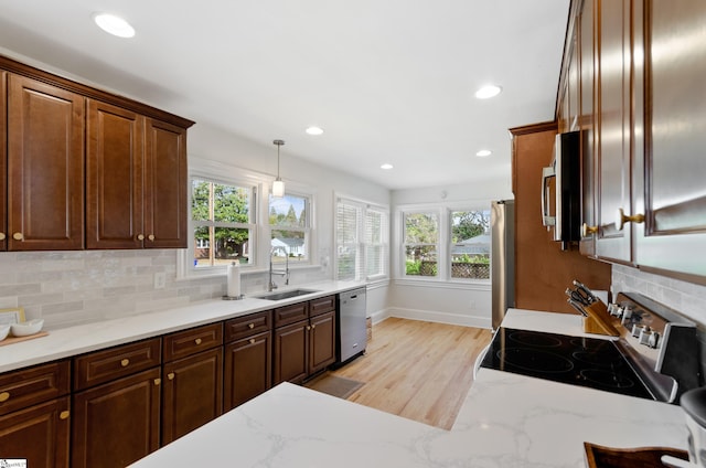 kitchen with hanging light fixtures, appliances with stainless steel finishes, decorative backsplash, and a sink