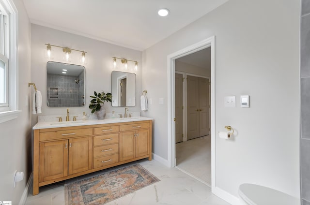 full bath with marble finish floor, double vanity, a sink, and baseboards