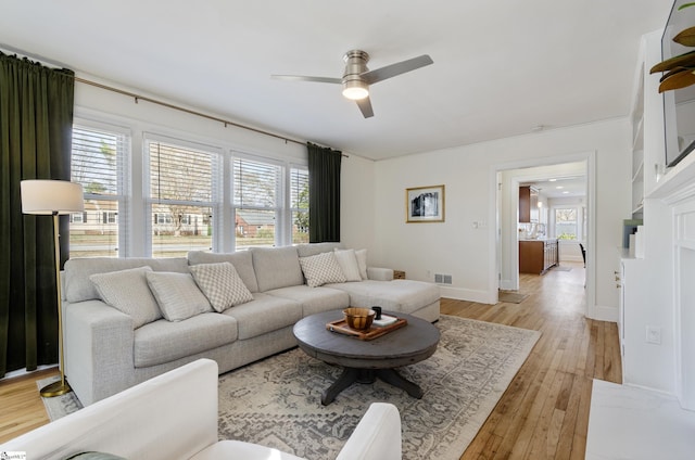 living room featuring light wood finished floors, plenty of natural light, and a ceiling fan