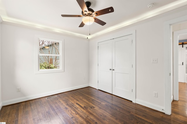 unfurnished bedroom with ceiling fan, visible vents, baseboards, a closet, and dark wood-style floors