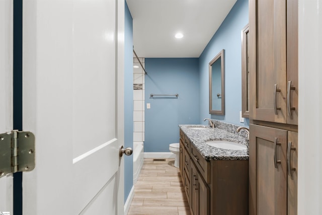 bathroom featuring double vanity, wood finish floors, a sink, and toilet