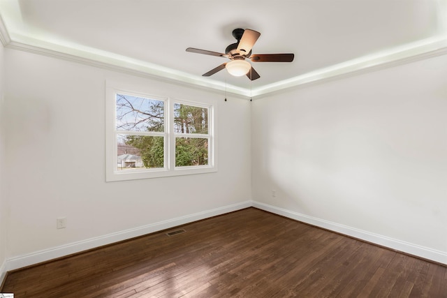 spare room featuring visible vents, baseboards, dark wood finished floors, ceiling fan, and a tray ceiling