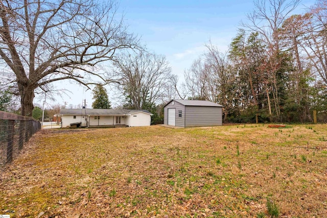 view of yard featuring fence, a storage unit, and an outbuilding