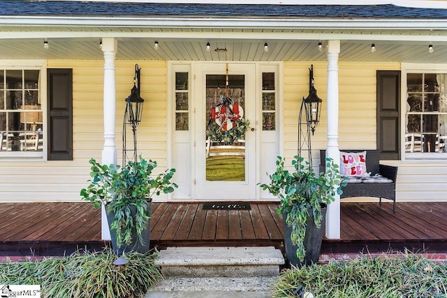 entrance to property with covered porch and roof with shingles