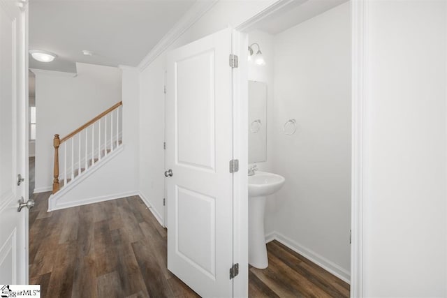 bathroom with a sink, crown molding, wood finished floors, and baseboards