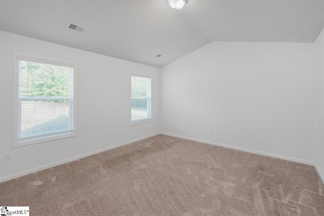 empty room with carpet, visible vents, vaulted ceiling, and baseboards