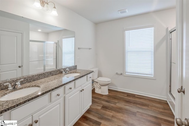 bathroom with a stall shower, visible vents, a sink, and wood finished floors