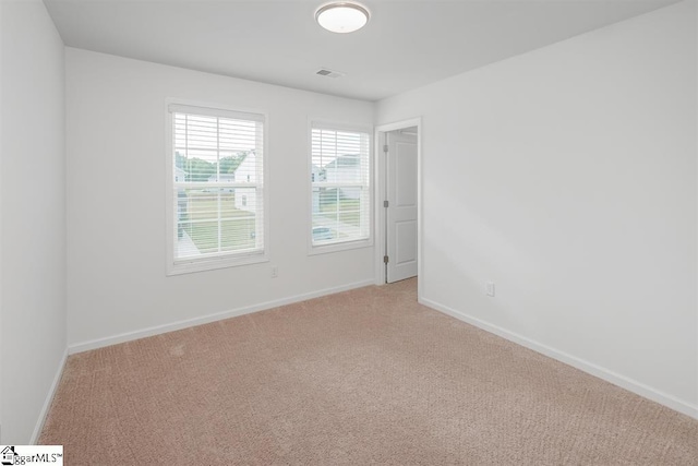 unfurnished room with light carpet and baseboards