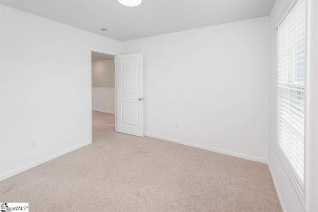 empty room featuring light carpet, baseboards, and a healthy amount of sunlight